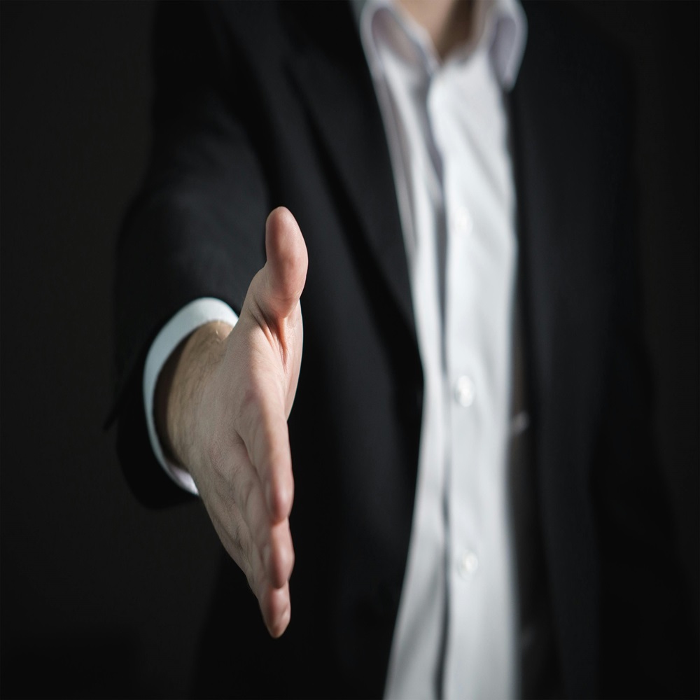 Businessman extending hand for handshake, symbolizing agreement, partnership, or professional collaboration.